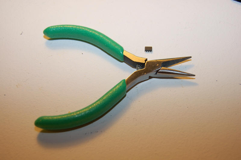 Tiny FRAM chip by small pair of long nose pliers.